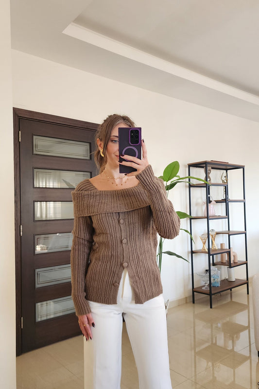 Person taking a mirror selfie wearing a brown cardigan and white pants in a modern interior setting.